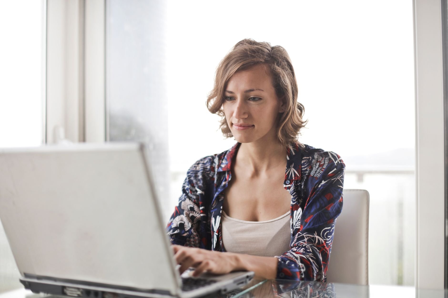A woman smiling with relief at her laptop, working comfortably from home