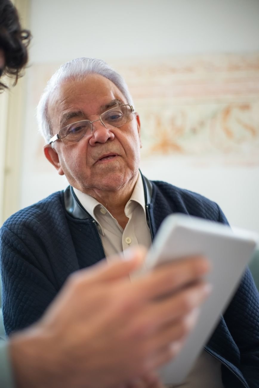 Senior man focused on a tablet, comfortably learning technology at home