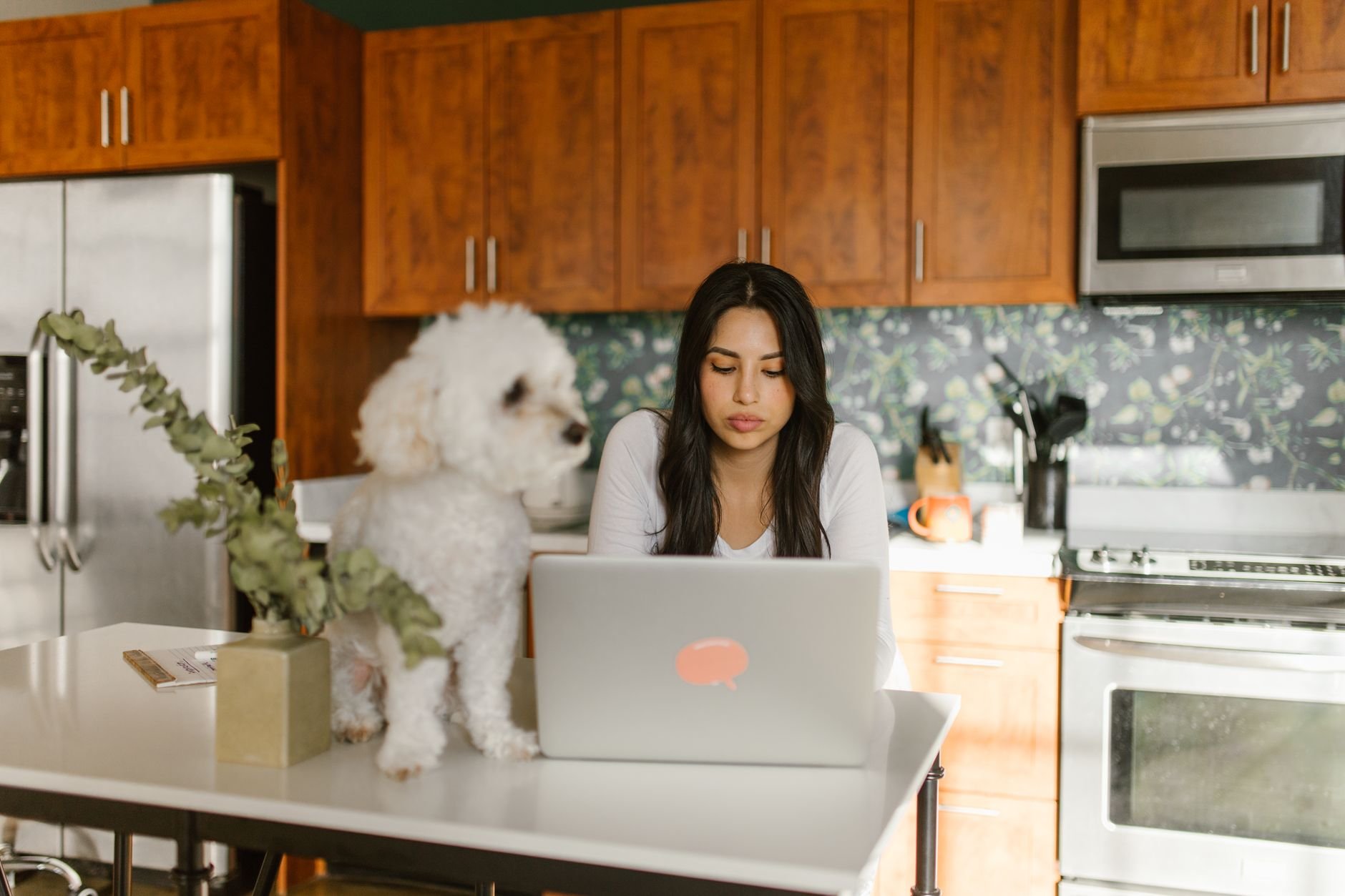 A woman smiling while using a laptop at home, relaxed and confident